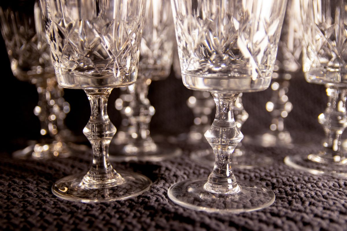 Close-up of intricately designed crystal wine glasses on a textured surface.