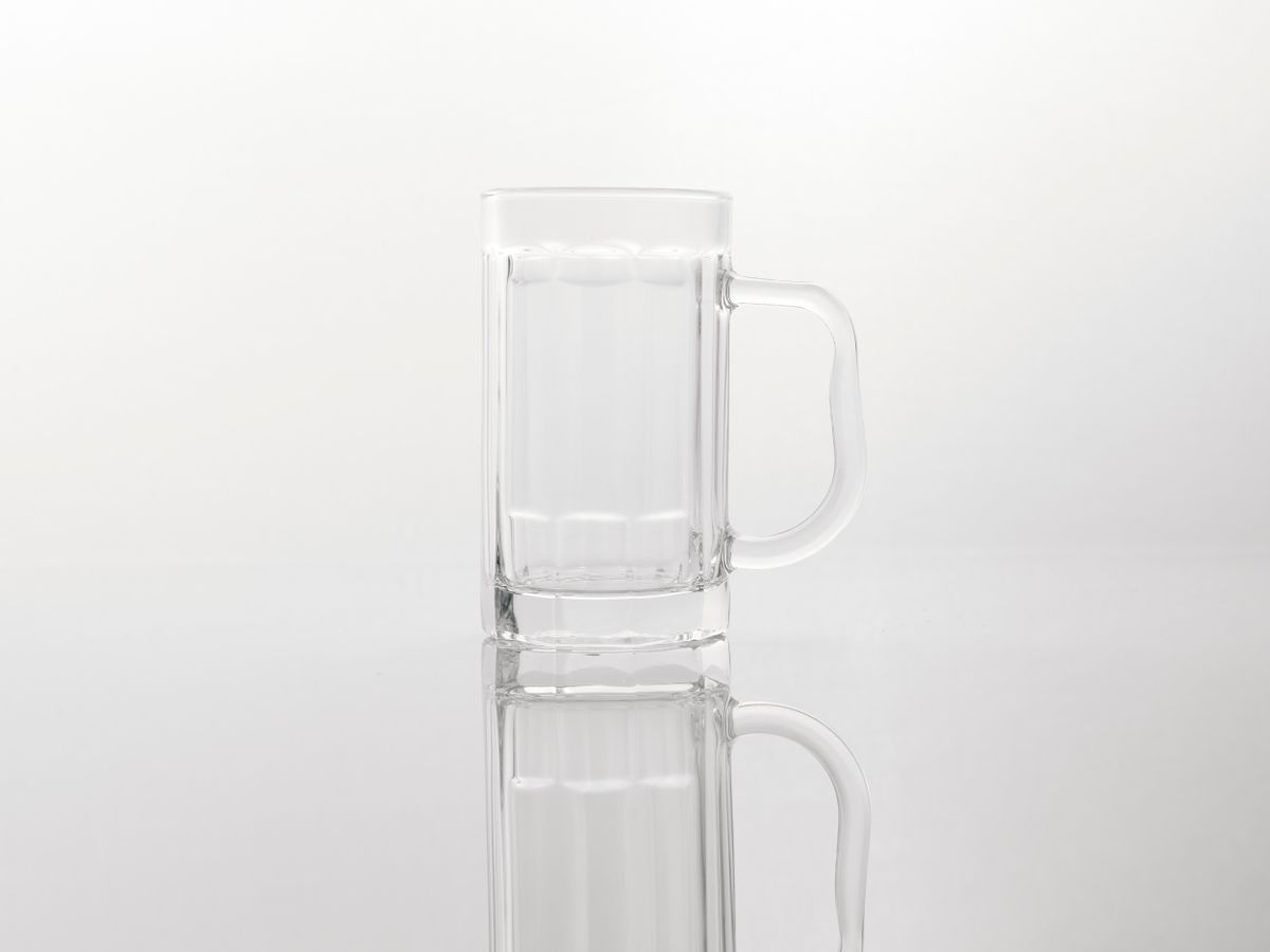 Minimalist clear glass mug with a reflection on a white background, perfect for product display.