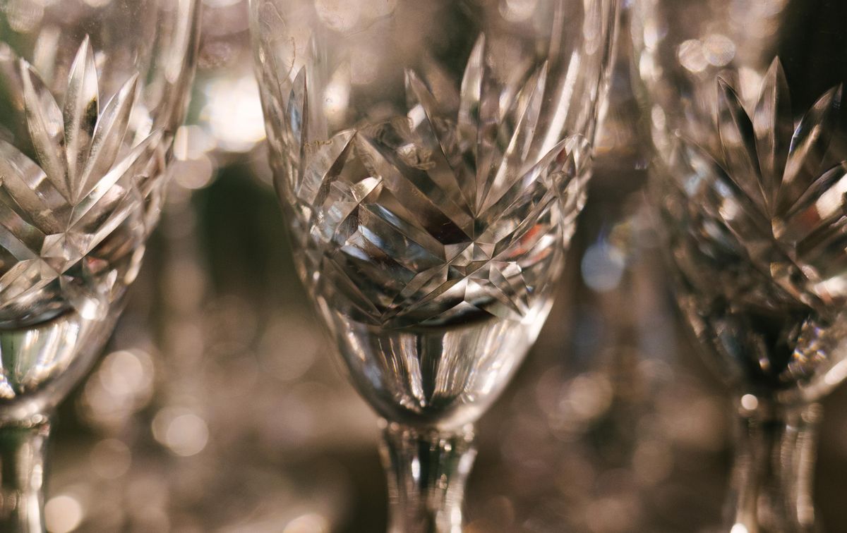 Detailed view of intricately designed crystal wine glasses reflecting light.