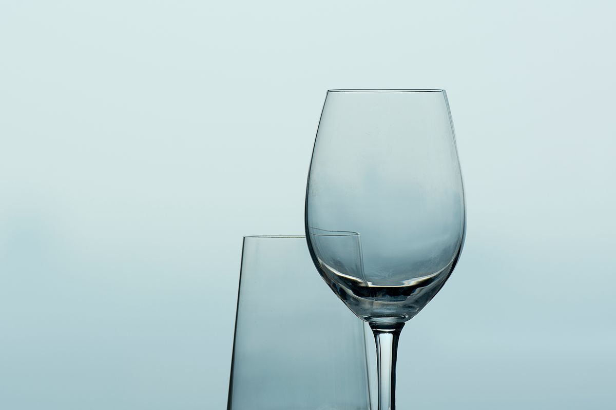 Two wine glasses elegantly displayed against a minimalist blue background, showcasing simplicity and style.