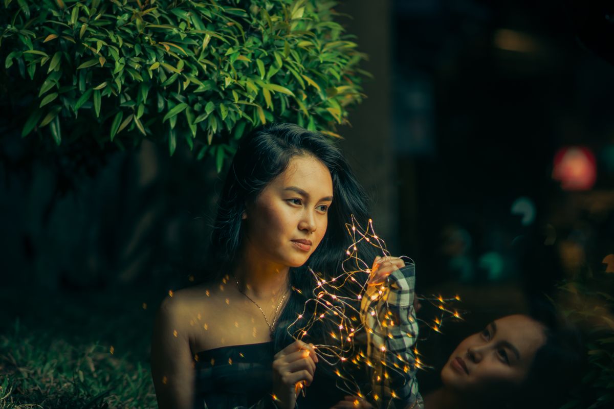 A woman holds fairy lights in a serene outdoor setting, creating a dreamy and mystical atmosphere.