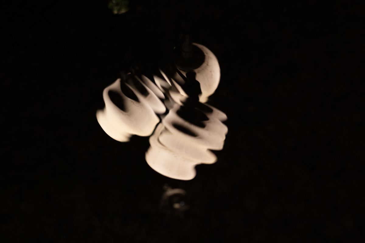 Abstract reflection of white hanging lights creating ripples in water at night.
