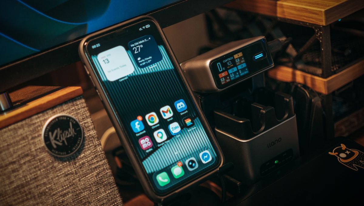 Smartphone and digital charging station on a desk with Klipsch speaker visible.