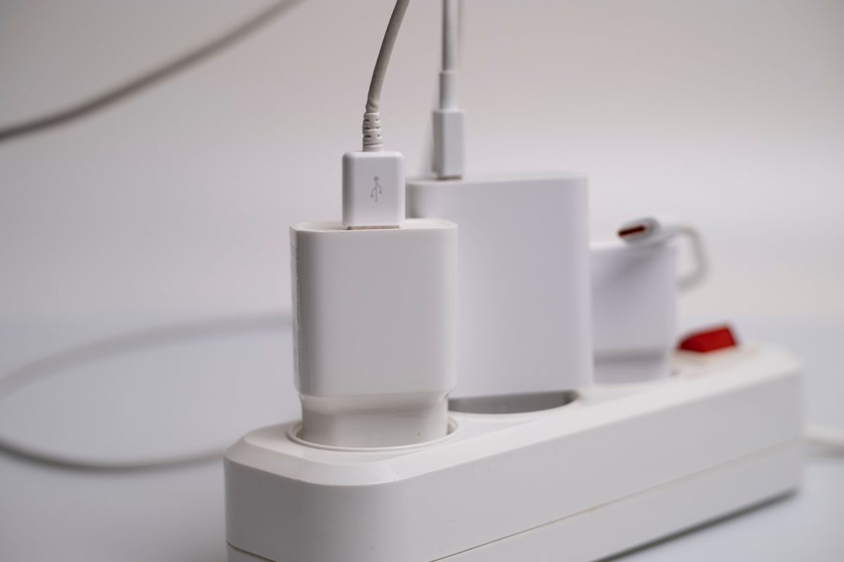Minimalist composition of electronic device chargers connected to a power strip indoors.