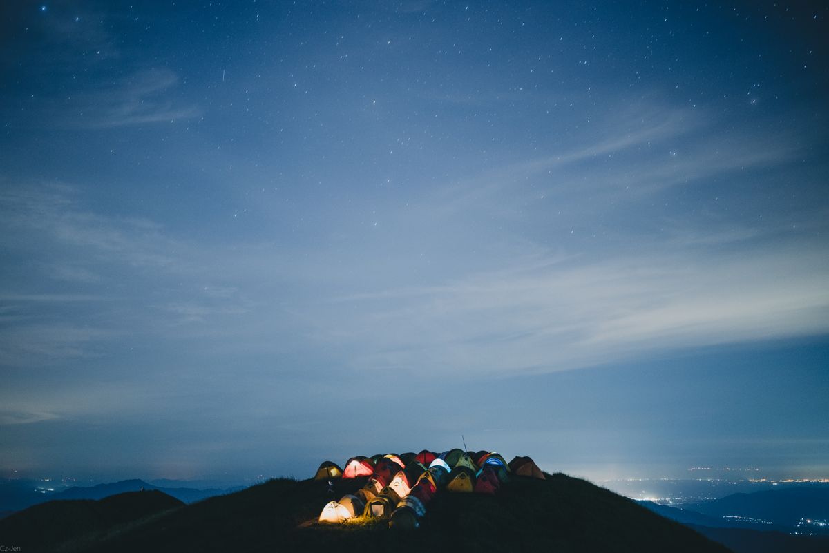 A serene night camping scene on a mountain in Pingxiang, Jiangxi, under a starry sky.