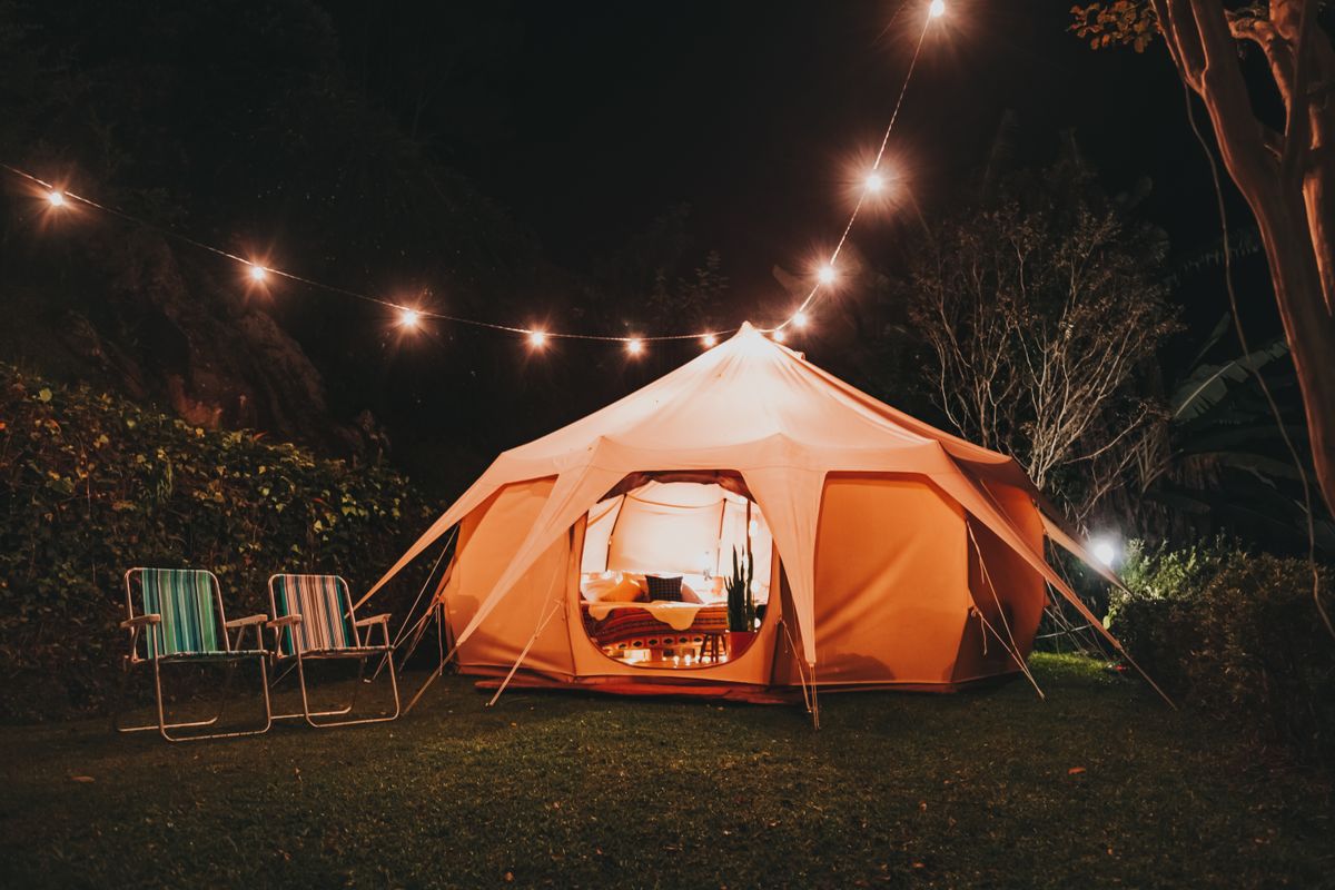 Explore a nighttime campsite with a cozy illuminated tent, perfect for a serene outdoor escape.