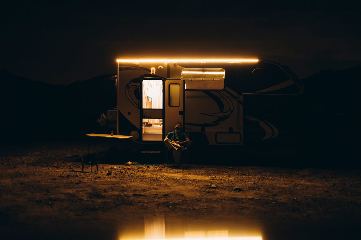 A serene night camping scene with a lit caravan under the Dubai desert sky.
