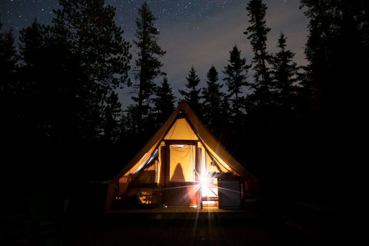 Glowing tent under a starry sky in the Quebec forest, perfect for camping adventures.