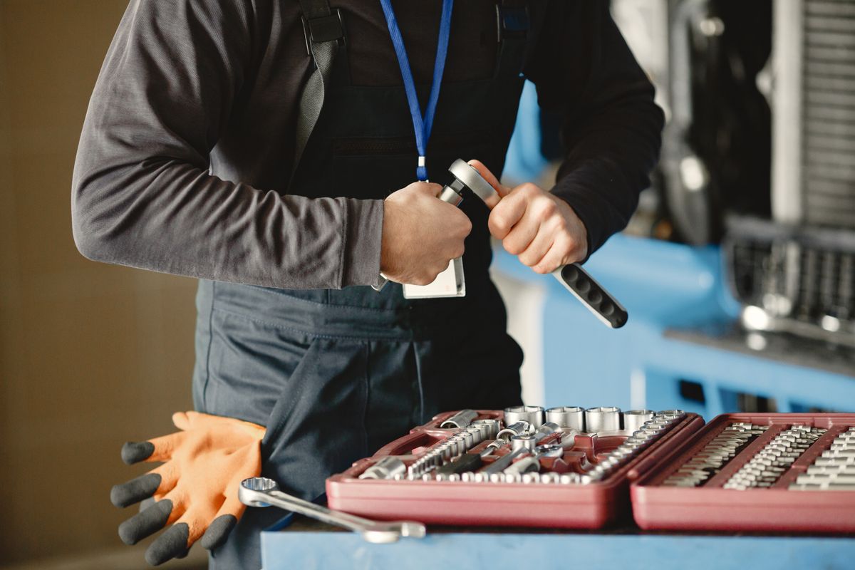 A mechanic in overalls prepares tools from a toolbox for vehicle repair service.