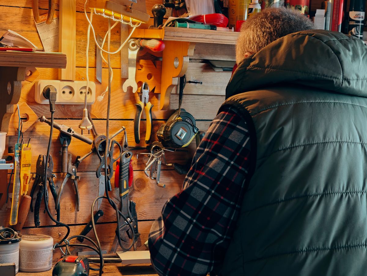 A person working in a wood-paneled workshop surrounded by tools.