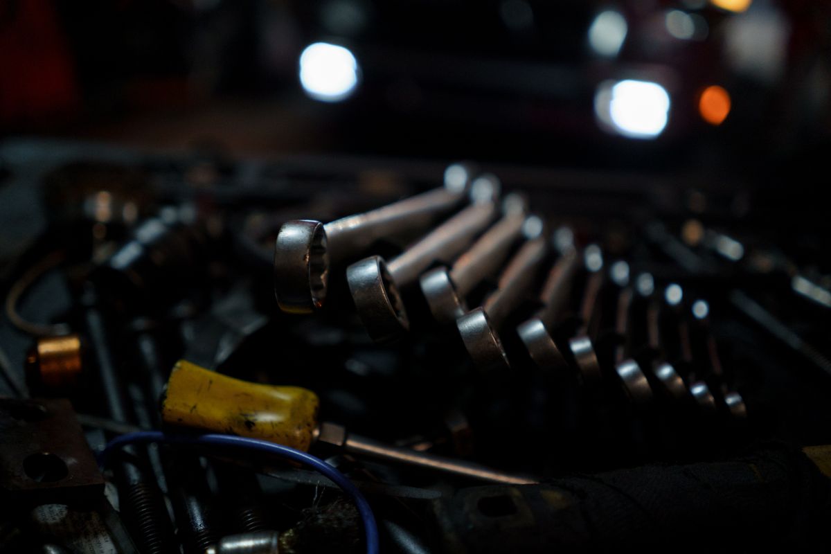 A detailed shot of various tools arranged with focus on wrenches in a garage environment.