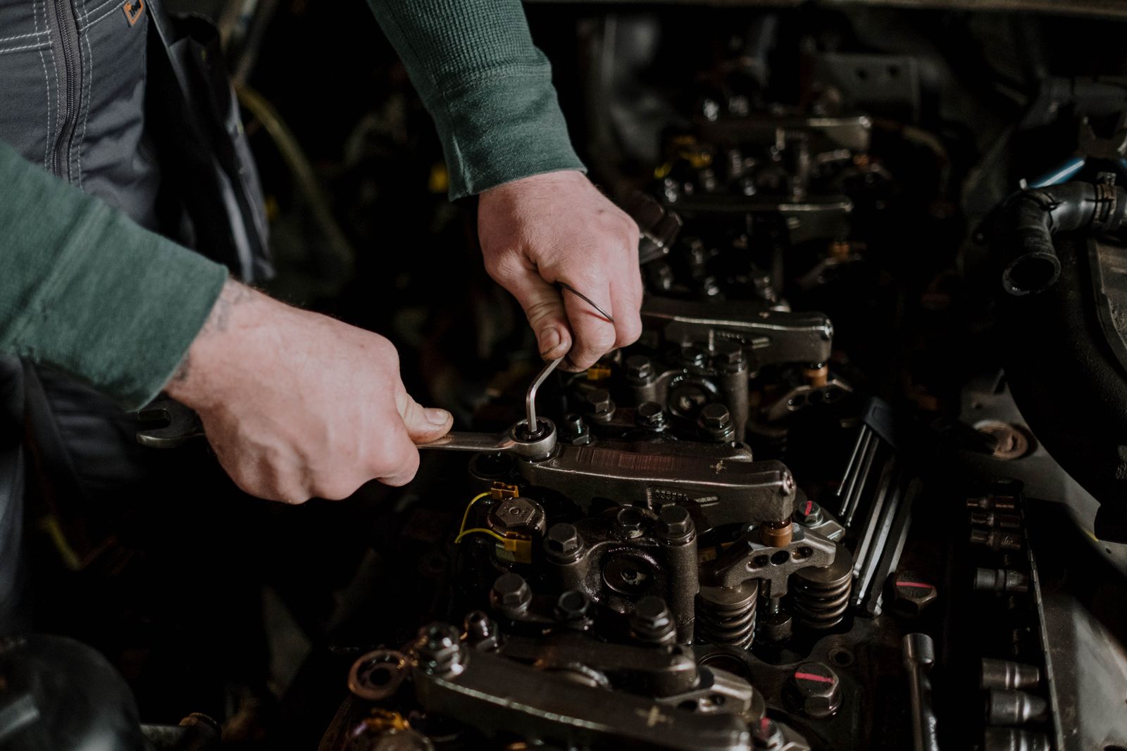 Close-up of a mechanic using hand tools to fix an engine, showcasing precision and skill.