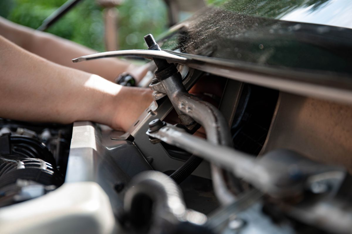 Close-up shot of a mechanic repairing a car engine with focus on tools and hands.