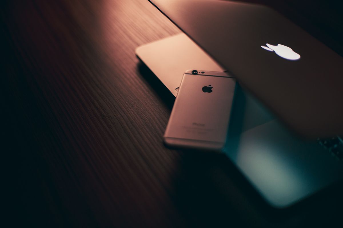 Modern tech setup featuring laptop and phone with ambient lighting on a wooden desk.