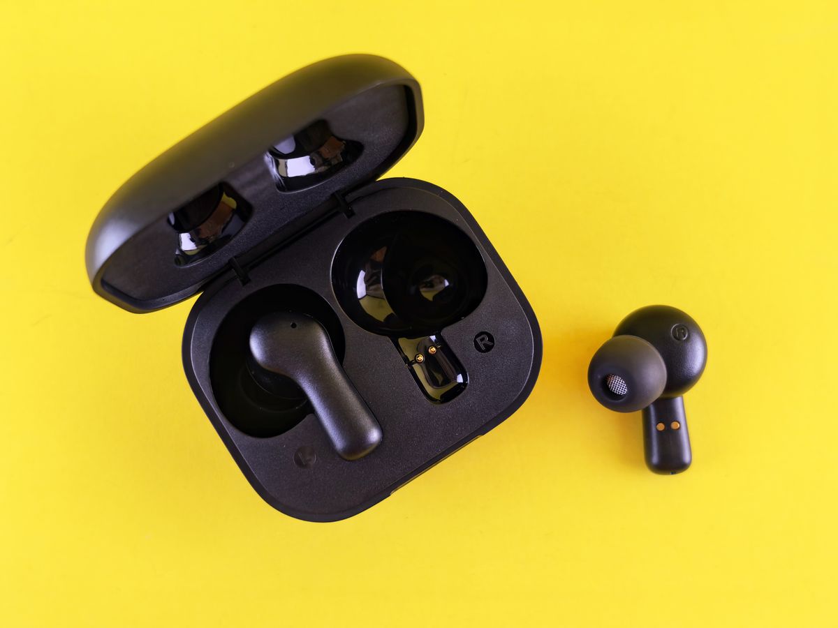 Close-up of black wireless earbuds and charging case on a vibrant yellow background.