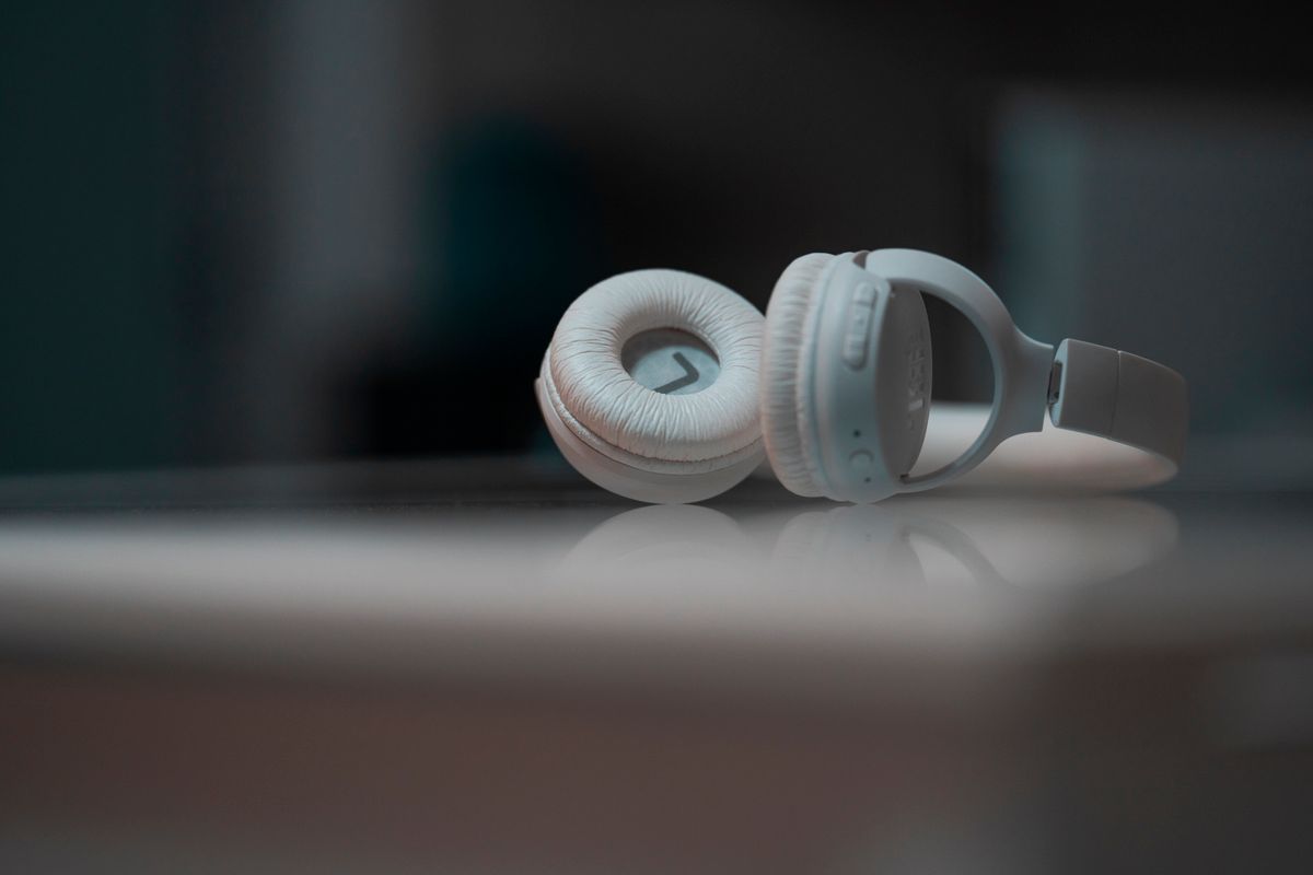 Close-up view of white headphones on a reflective surface, showcasing modern audio technology.