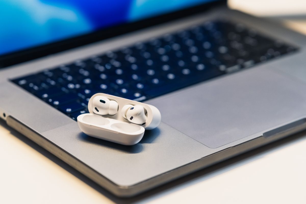 Close-up of wireless earbuds in case resting on an open laptop, highlighting modern technology.