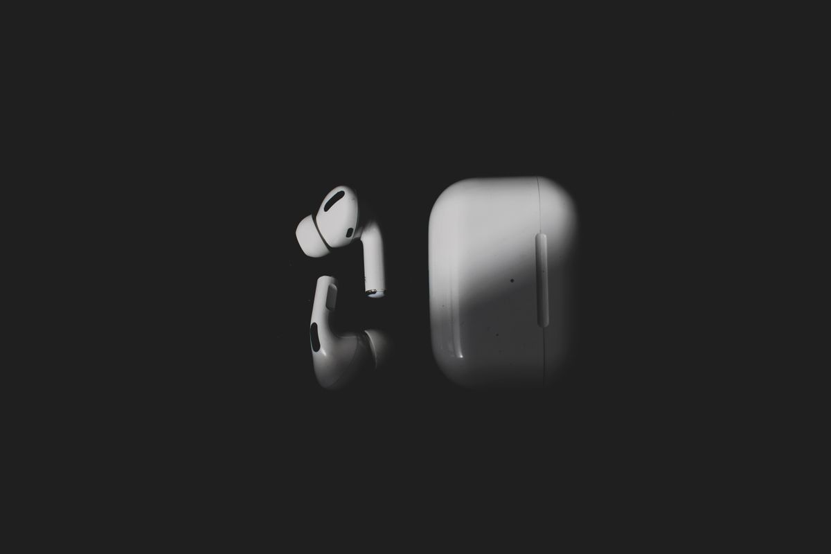 Stylish wireless earbuds and charging case on a sleek black background, featuring modern tech design.
