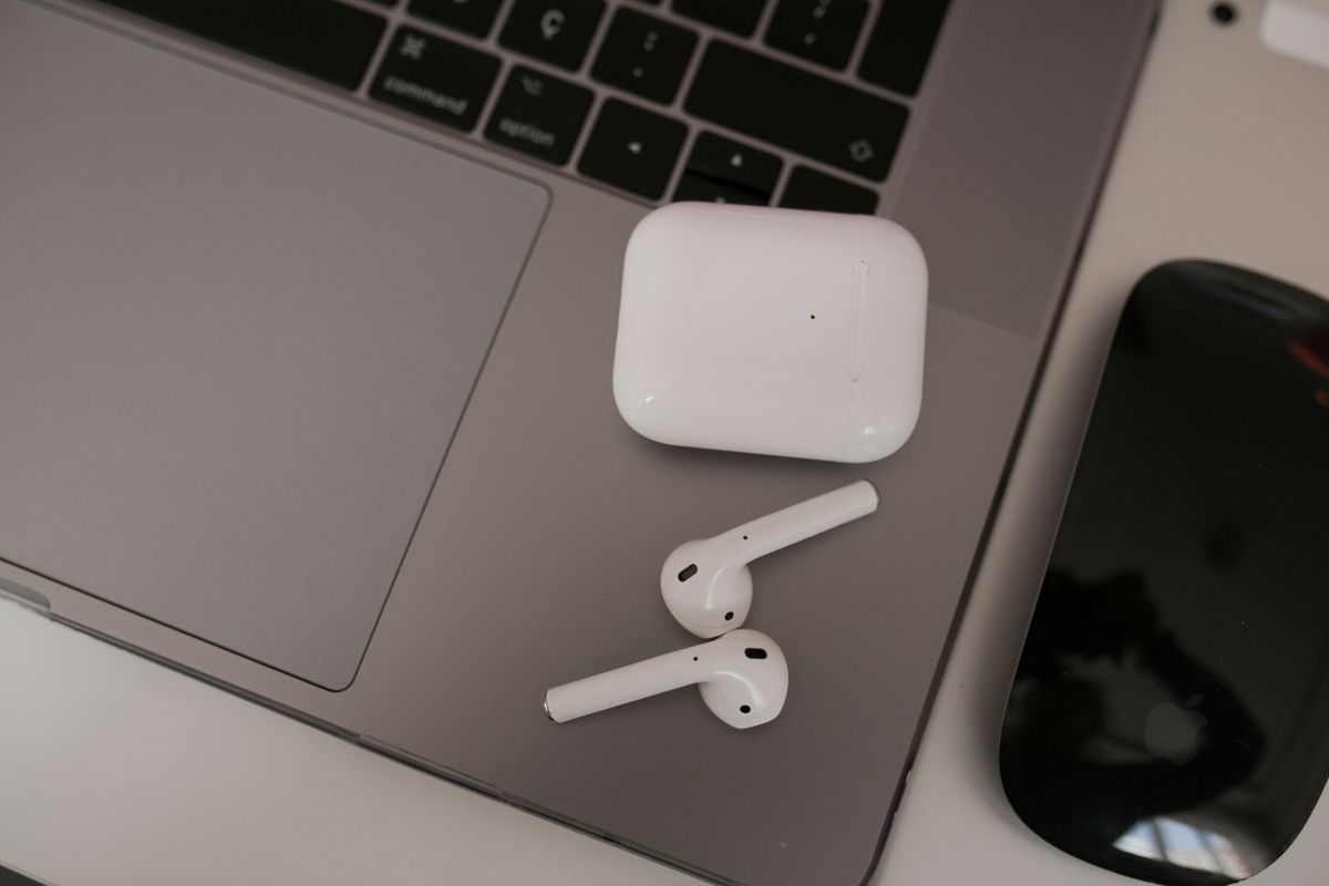 Close-up of wireless earbuds and case on a laptop, highlighting modern tech usage.