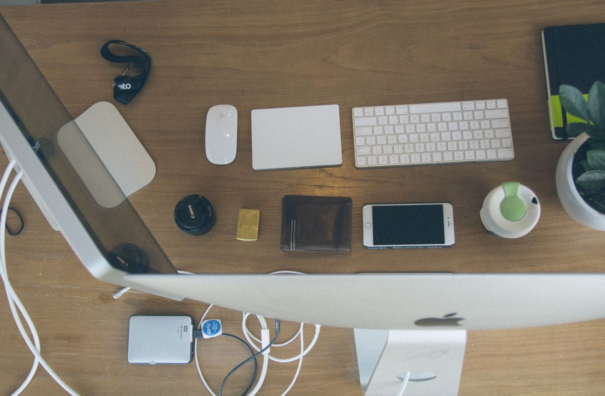 Top-down view of an organized modern desk setup featuring Apple devices and accessories.