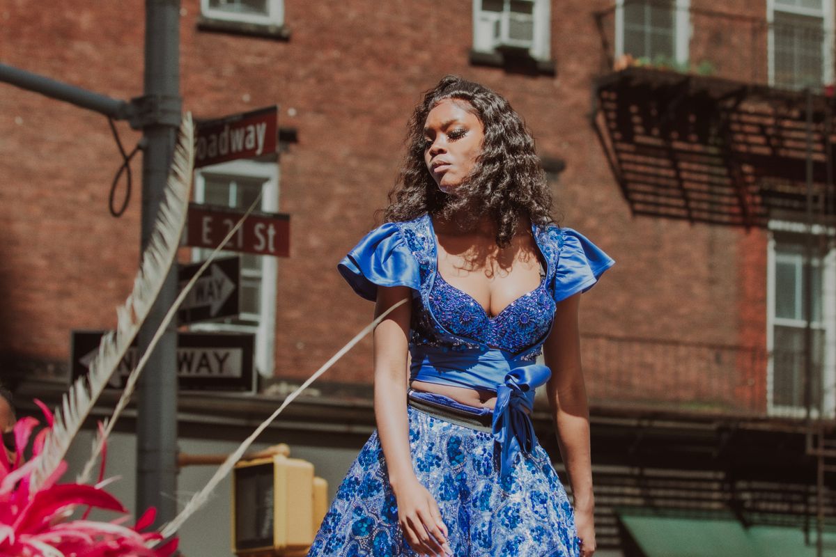 Woman in a vibrant blue dress enjoying a sunny day in New York City.