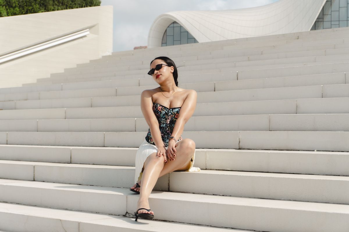 Elegant woman posing on stylish architectural steps in Baku, showcasing fashion and glamour.