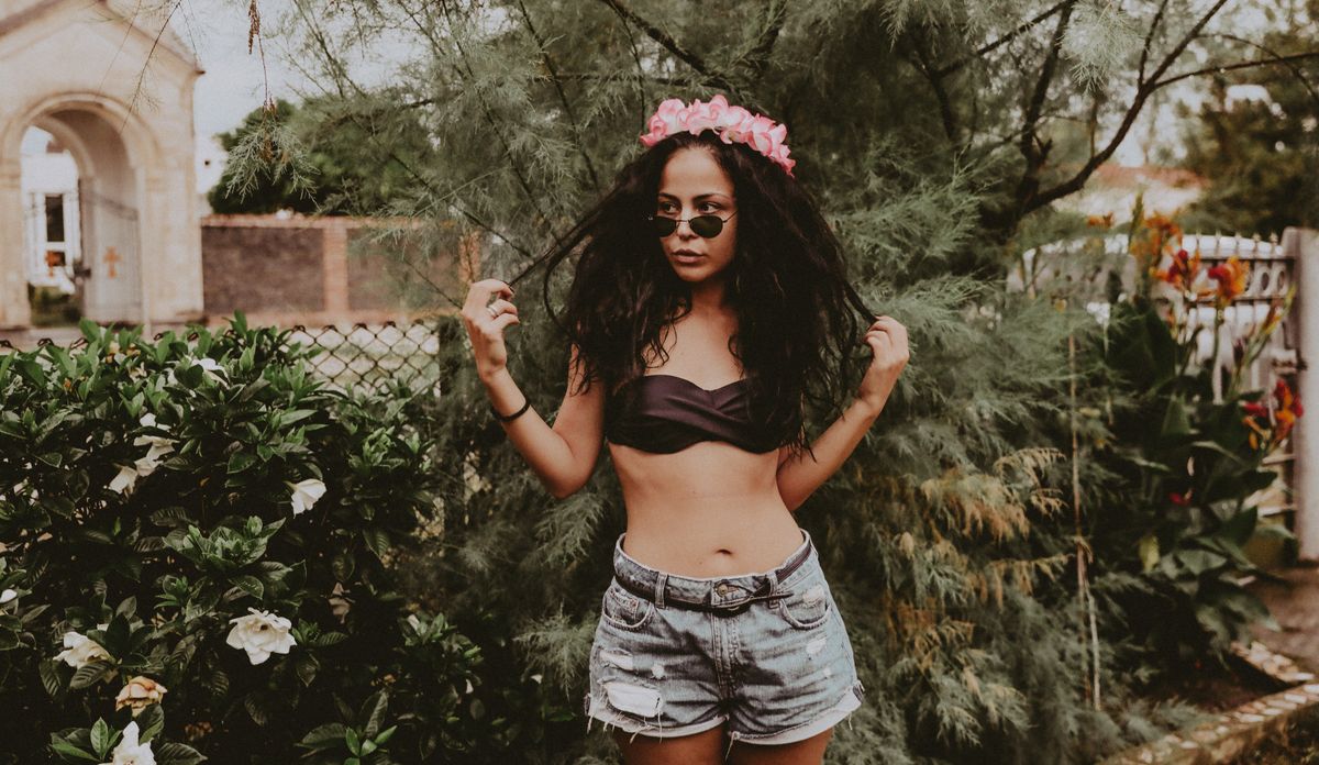 Stylish woman in shorts and flower crown striking a pose outdoors.