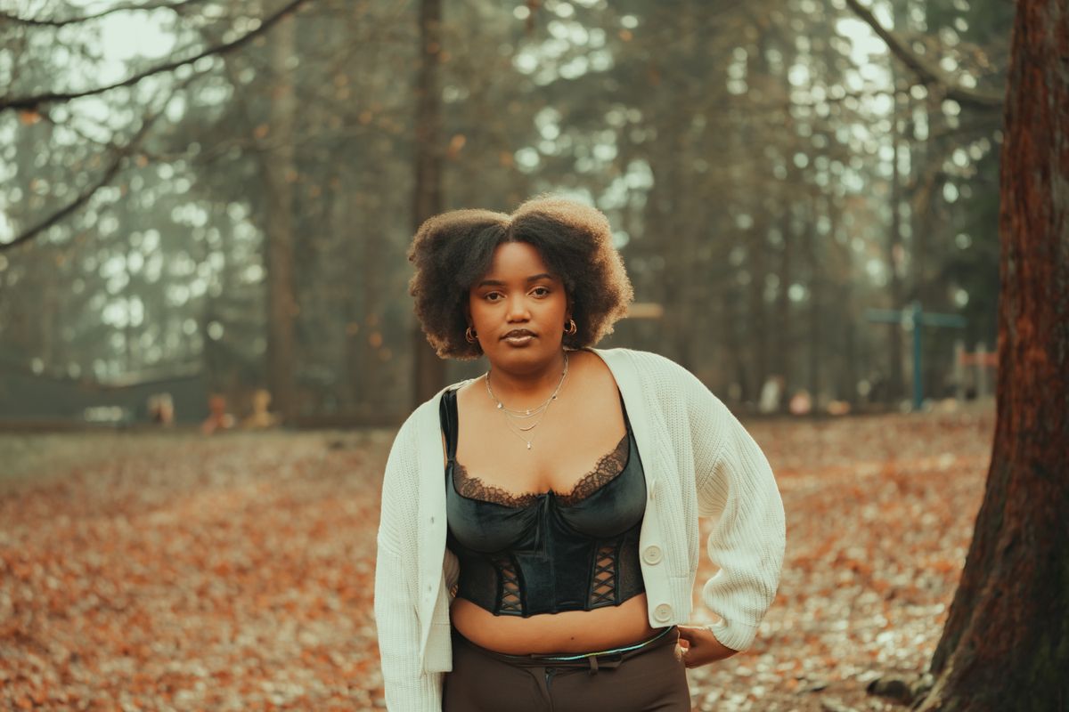 Elegant portrait of a woman in autumn fashion amidst a serene forest backdrop.