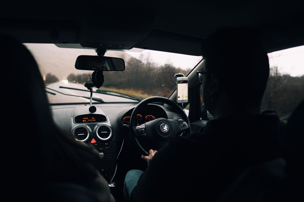 Couple driving through scenic Scottish countryside on a rainy day, inside car view.