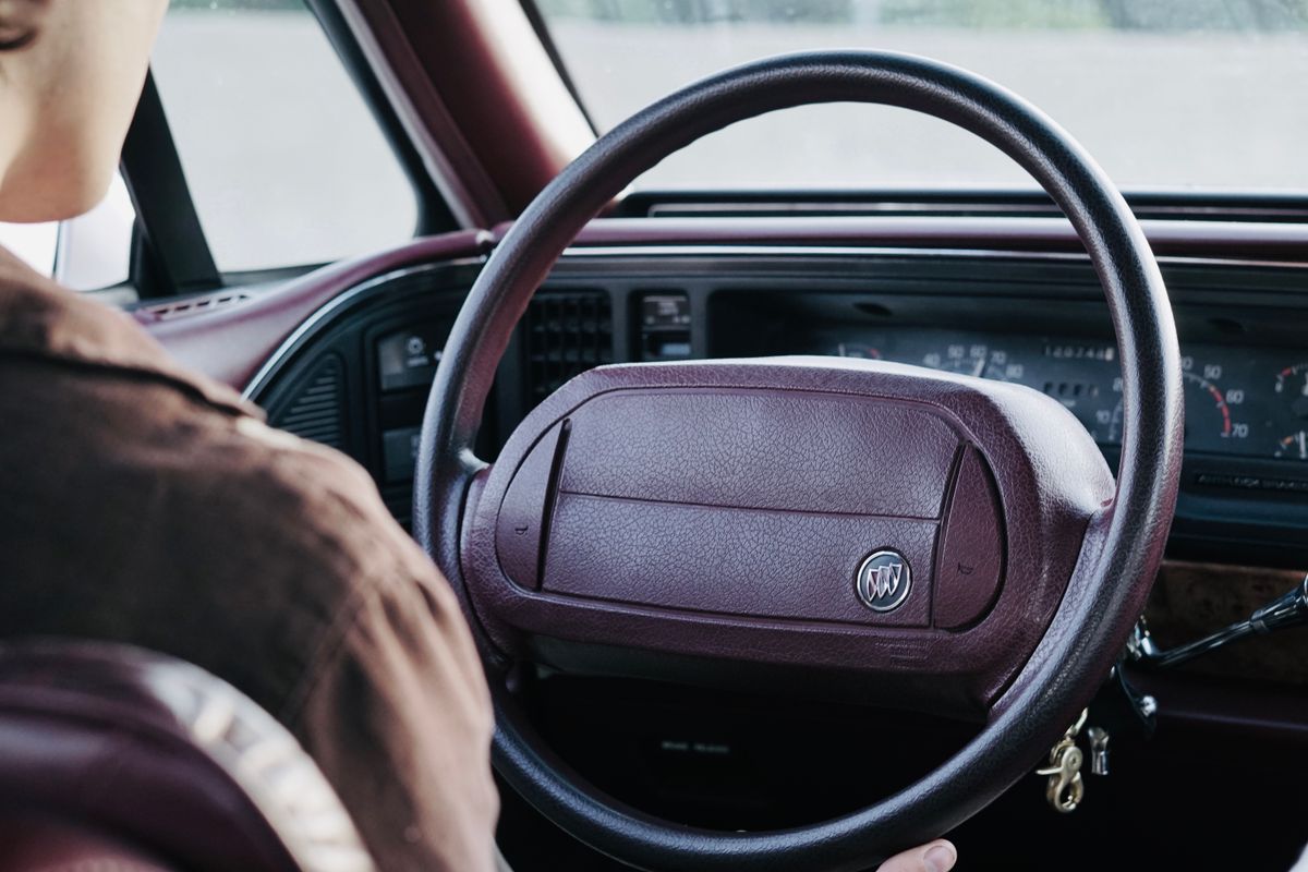 Detailed view of a classic car interior and steering wheel with driver.