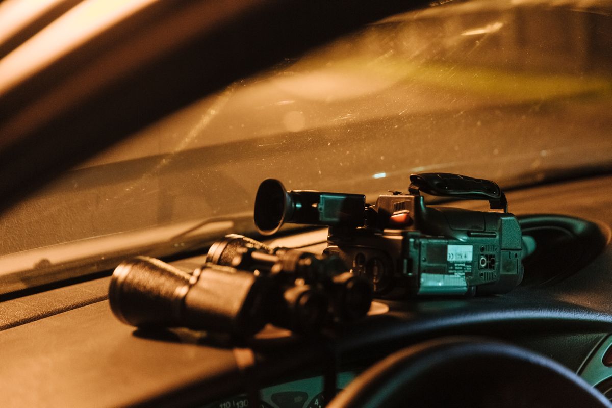 Close-up of a camcorder and binoculars on car dashboard captured at night.
