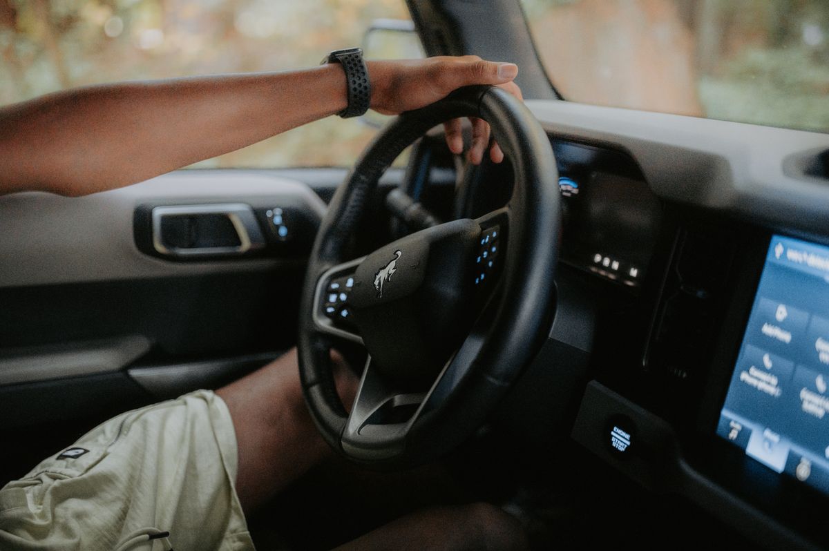 A person driving a modern car, focusing on hands and steering wheel.