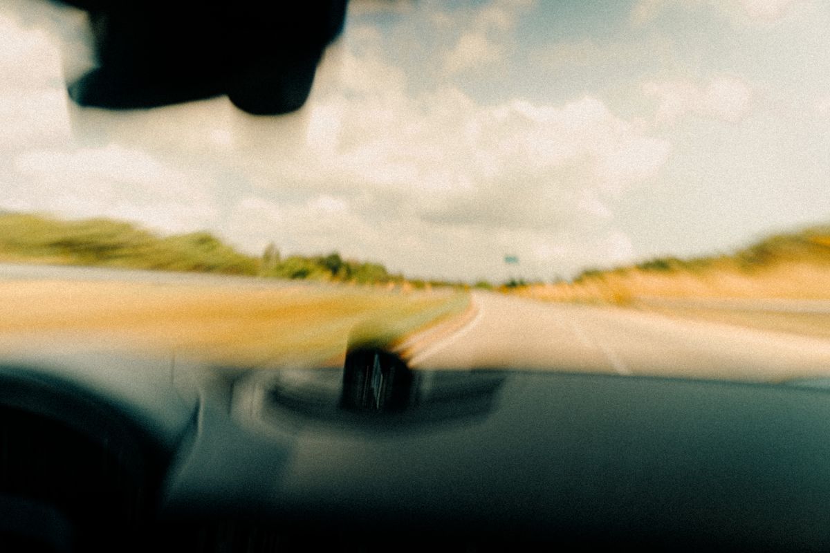 Dynamic blurred image from a vehicle's windshield capturing a rural road in motion.