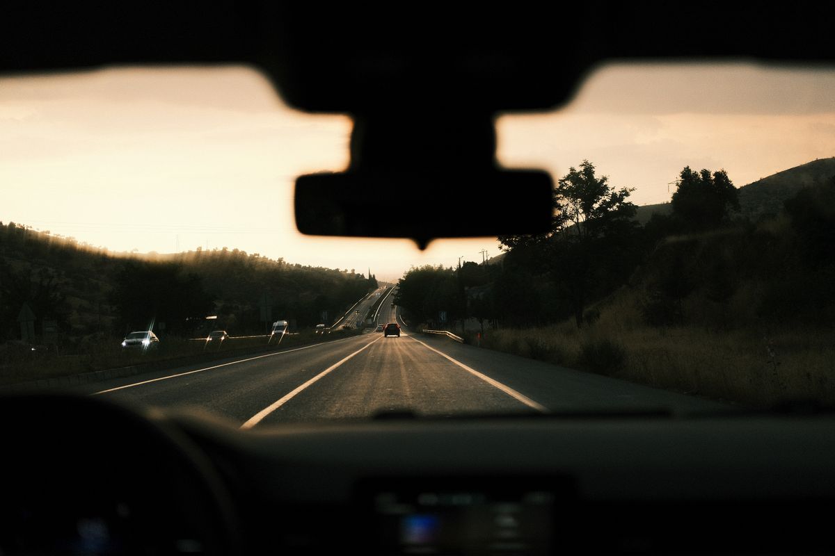 View through a car windshield of a scenic highway during sunset, capturing the road trip vibe.