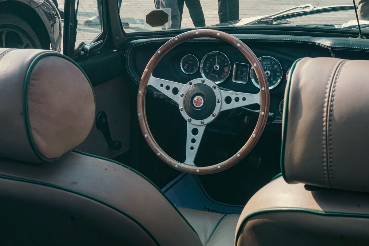 Vintage car interior showcasing a classic wooden steering wheel and dashboard gauges.