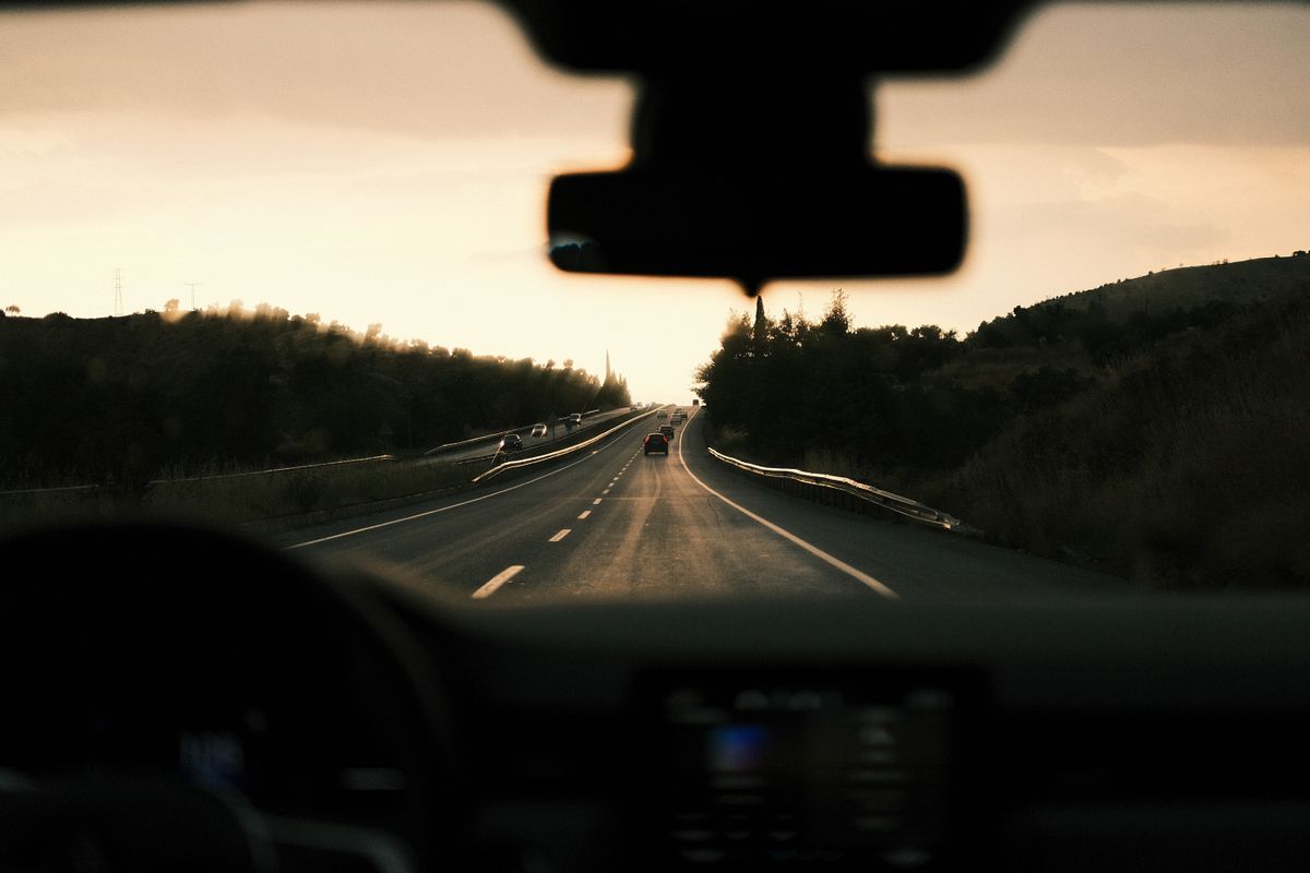 A picturesque view from inside a car driving towards the sunset along a peaceful highway.