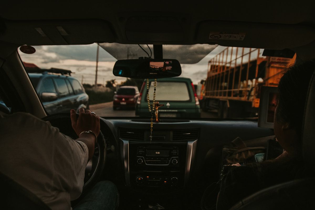 View from inside a vehicle stuck in traffic on a busy Philippine road during sunset.