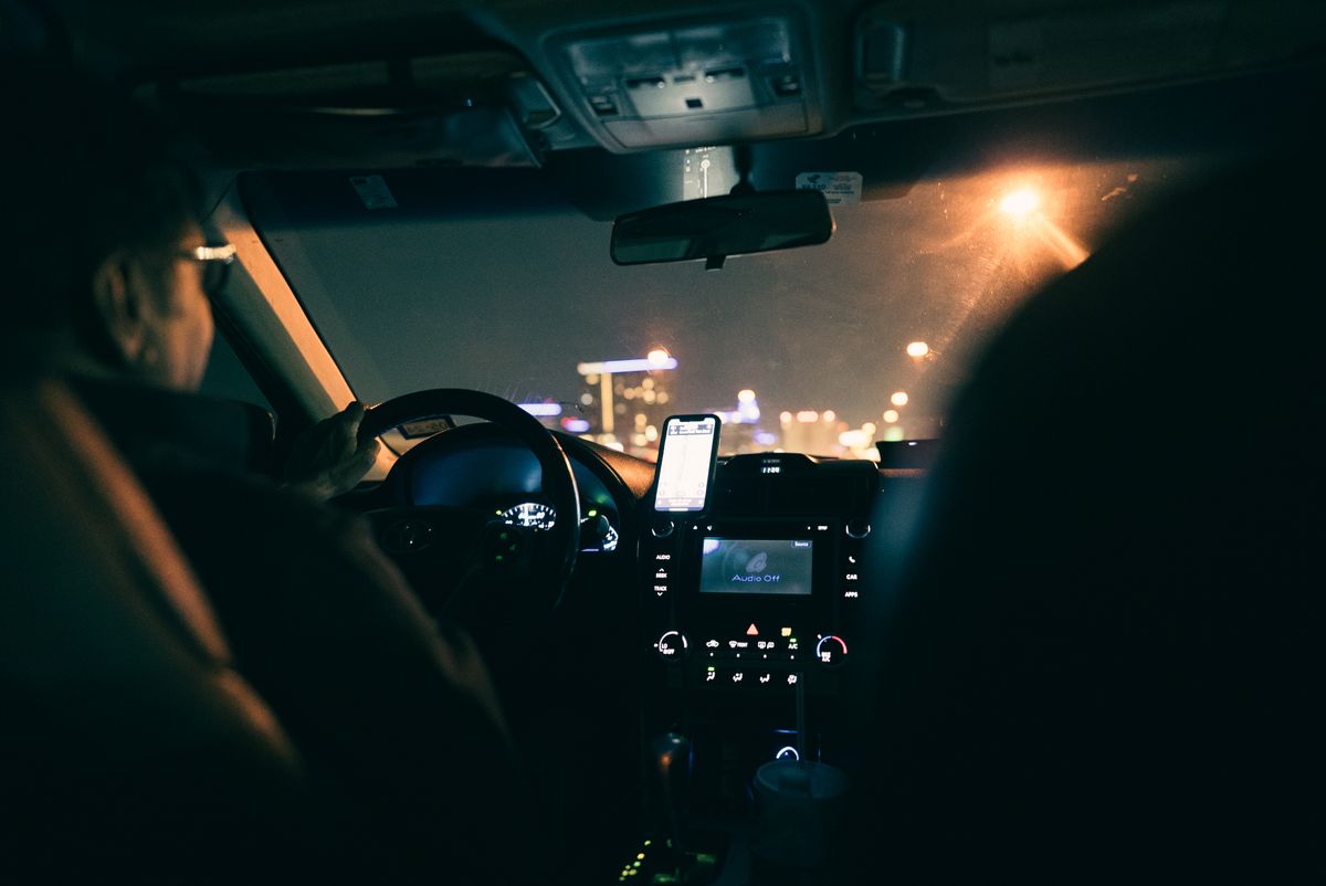 View from inside a car showing a driver navigating a city at night using GPS.