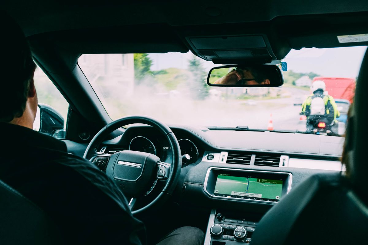 Interior view of a car with GPS navigation and traffic ahead, showcasing urban transportation.