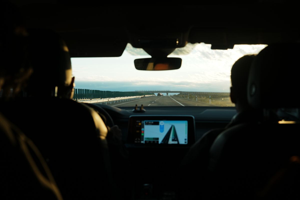 View from inside a car during a road trip showcasing an open highway and digital navigation screen.