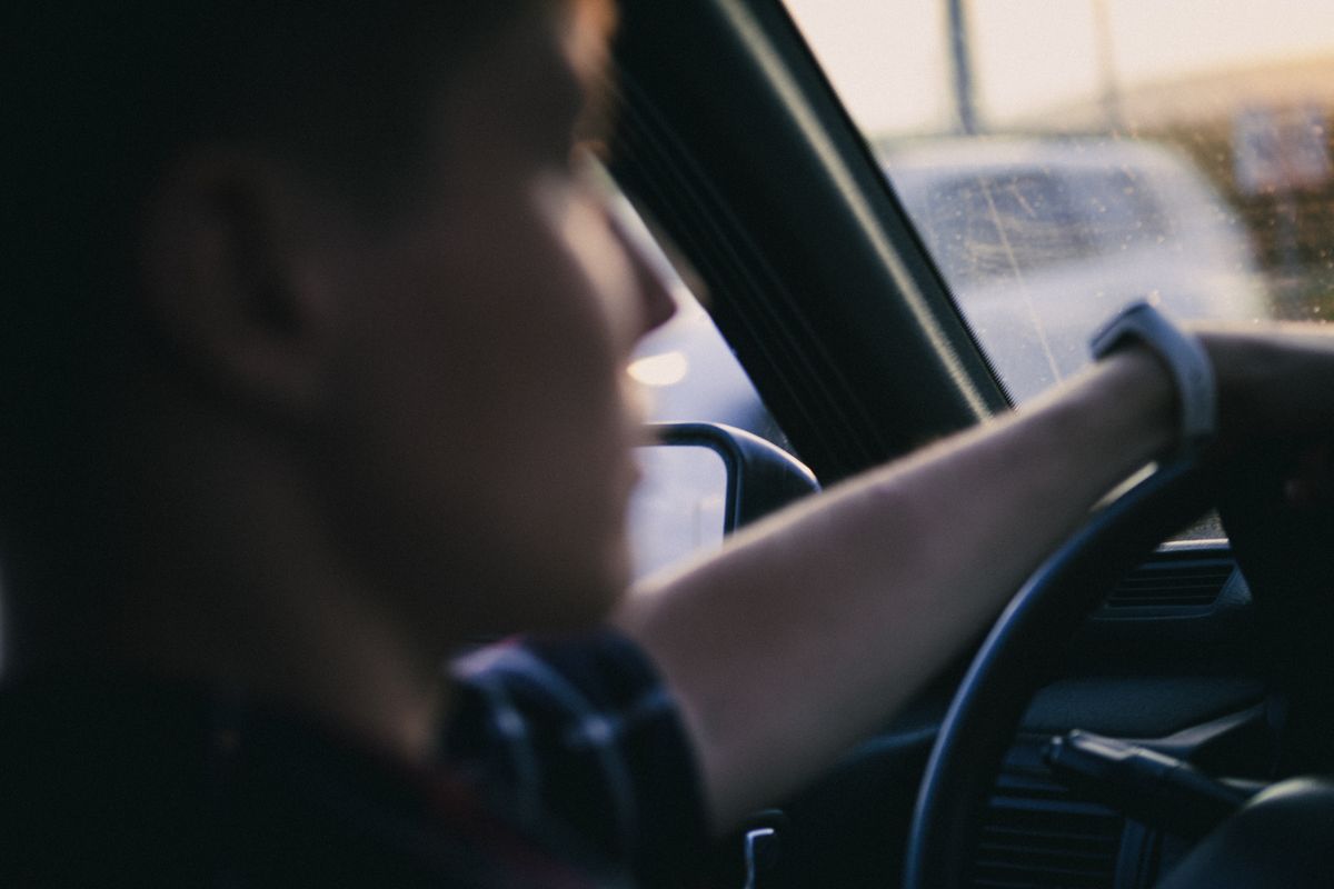 A close-up shot of a driver holding a steering wheel, focusing on the hand and interior details.