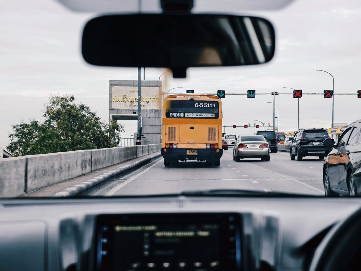 View of Bangkok traffic from inside a car, featuring buses, cars, and road signs.