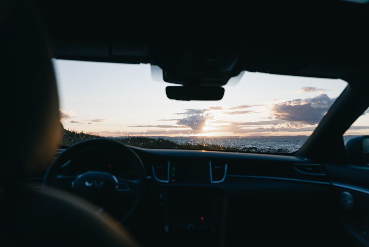 Scenic drive with ocean sunset view through car windshield, capturing a peaceful and contemplative moment.