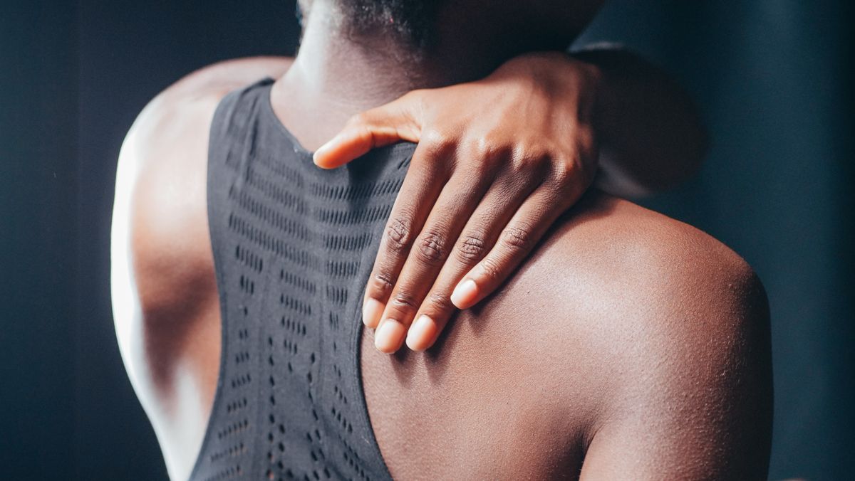 A close-up shot of a person touching their shoulder, emphasizing texture and form.
