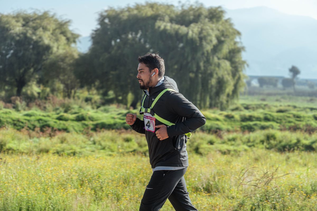 Man jogging in a lush park setting, engaging in fitness and exercise.