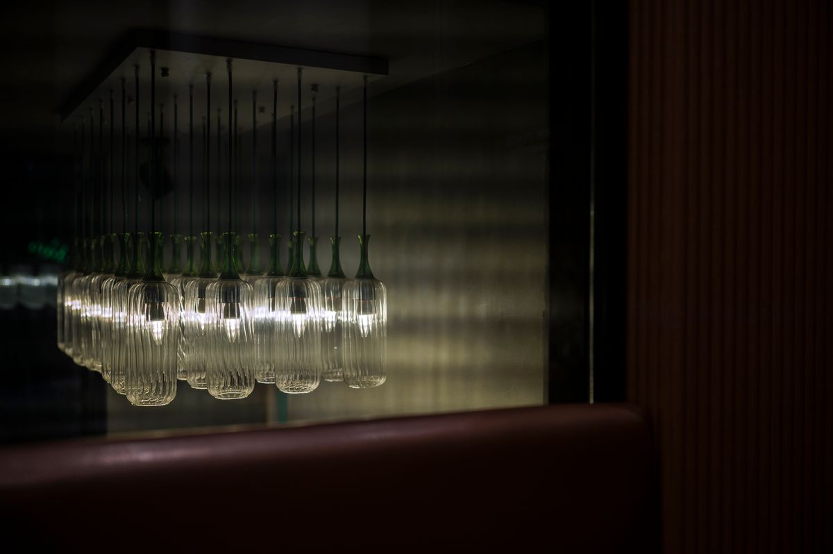 Artistic view of illuminated pendant lights reflecting on glass in a chic interior.