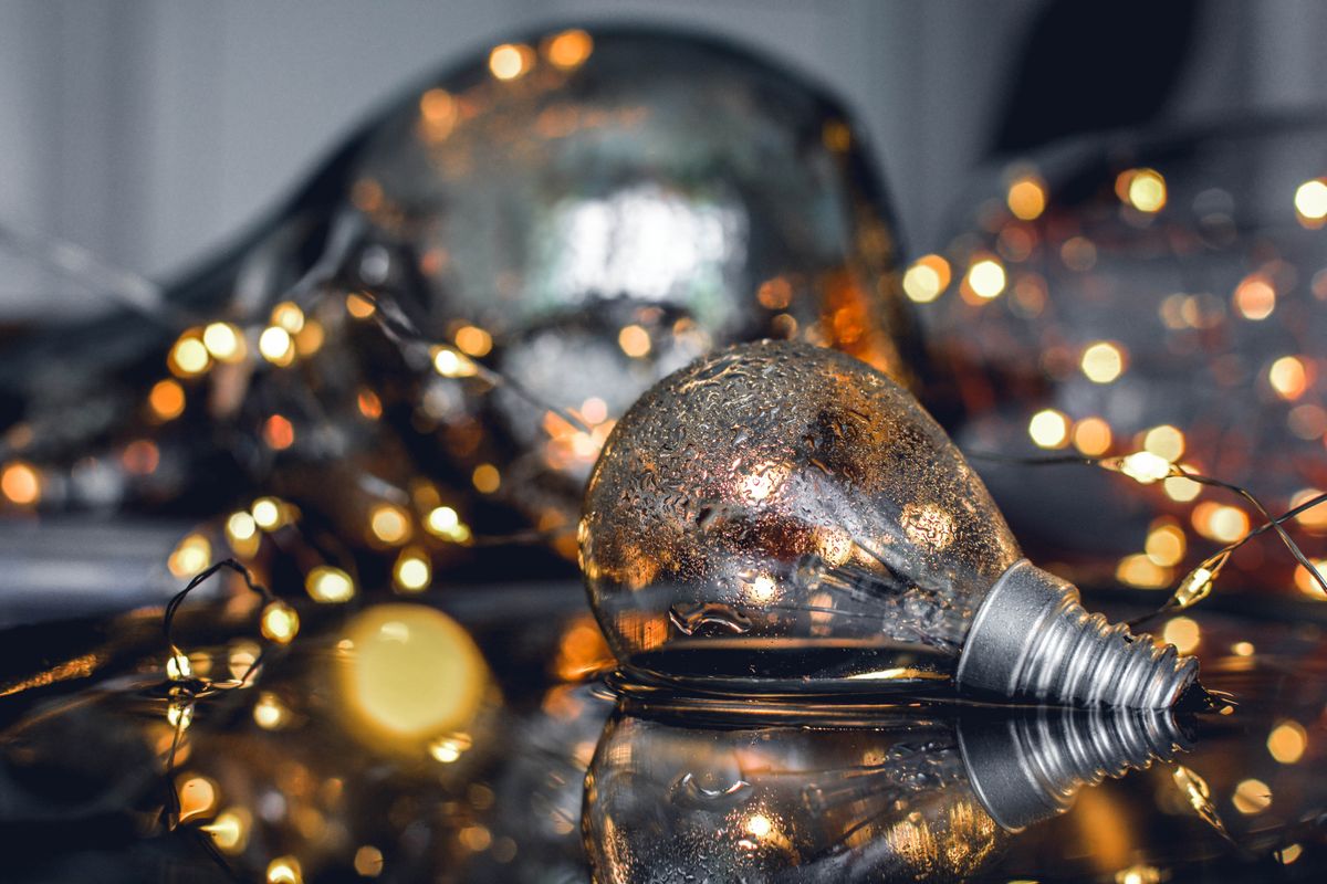 Close-up of wet light bulbs and fairy lights reflecting on a surface.