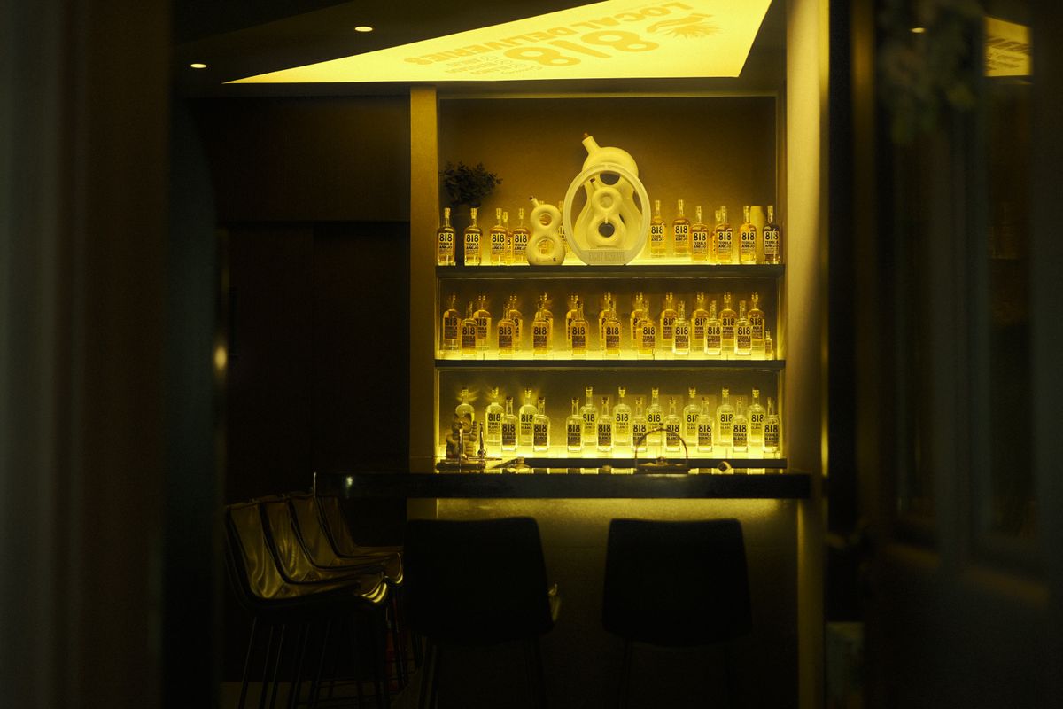 Intimate bar setting showcasing illuminated shelves with 818 Tequila bottles in warm lighting.