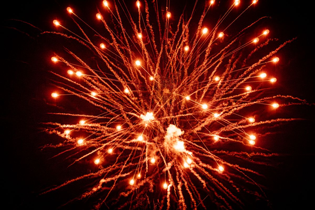A stunning explosion of orange fireworks lighting up the night sky, creating a vibrant display.