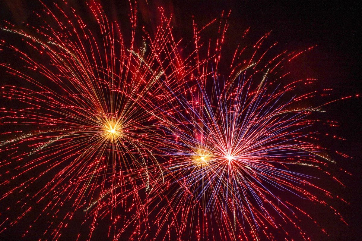 Vibrant red and blue fireworks lighting up the night sky in a stunning display.